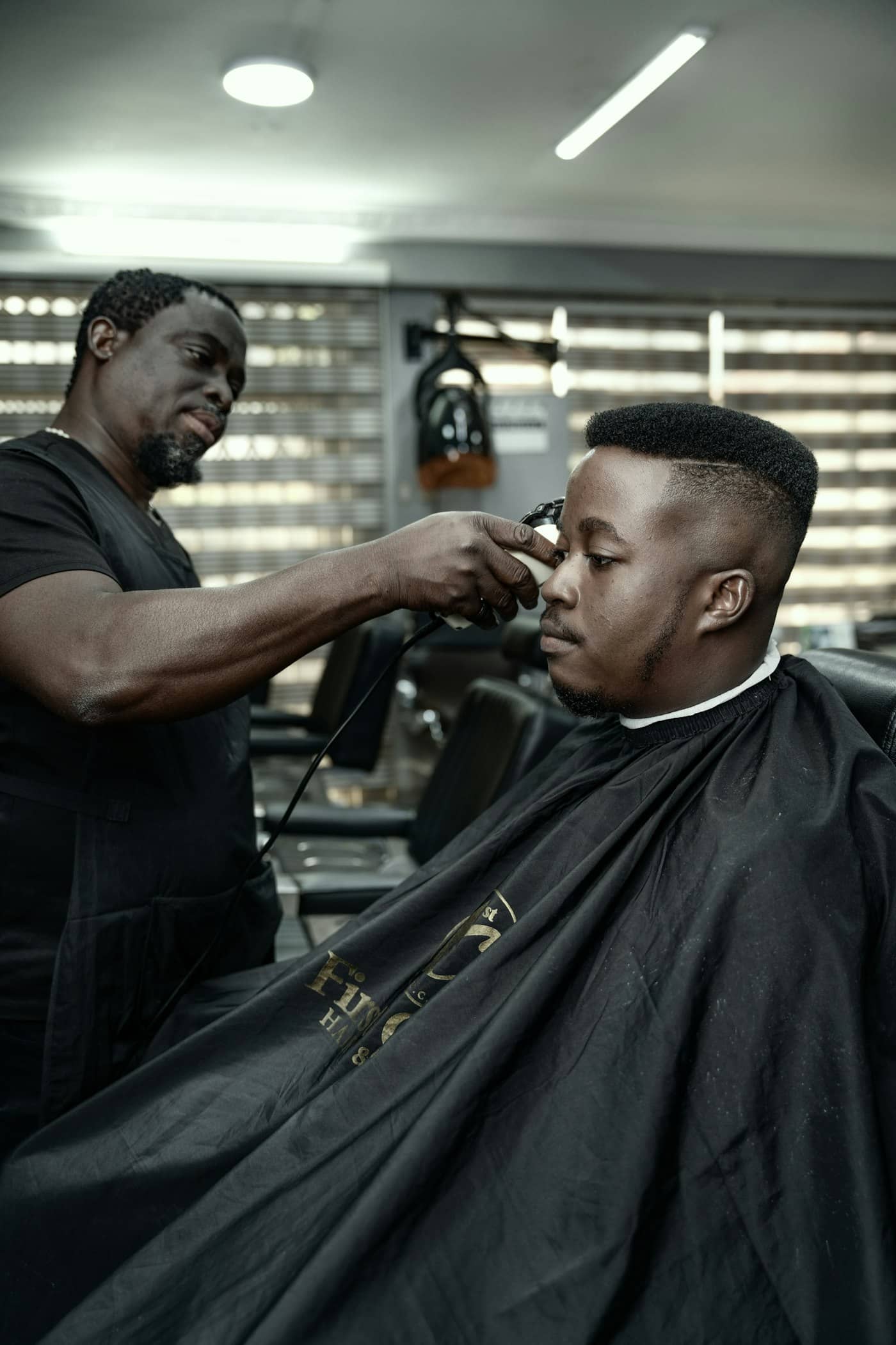 Barbier réalisant un dégradé à la tondeuse sur un client